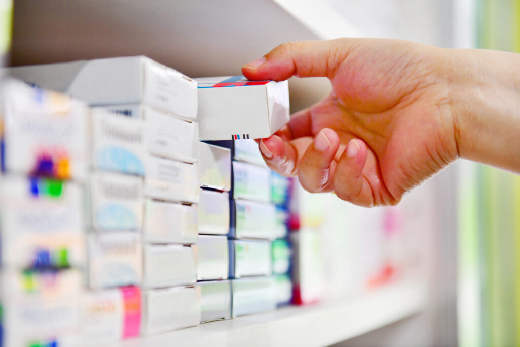 grabbing medicine from a pharmacy shelf